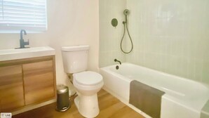 Een badkamer met toilet, wastafel en bad.