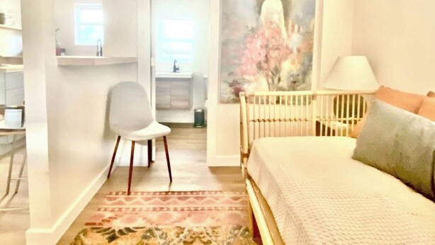 Een slaapkamer met een bed, een stoel, een schilderij en uitzicht op de badkamer.