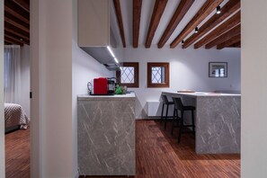 A modern kitchen with marble countertops, wooden beams, and a dining area with bar stools.