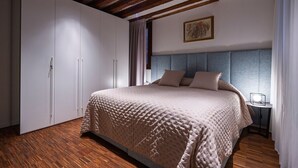 A bedroom with a large bed, a wardrobe, and a nightstand.