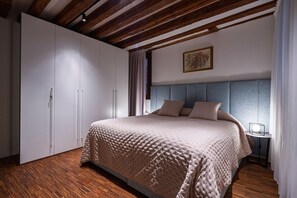 A bedroom with a large bed, a wardrobe, and a nightstand.