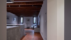 A modern interior with a wooden ceiling, a marble counter, and a seating area with a chair and a small table.
