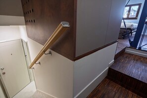 Un escalier avec une rampe en bois et un mur blanc avec une porte.