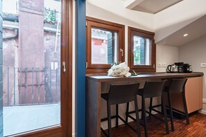 A kitchen with a bar area, two windows, and a view of the outside. - Ca' Vida Terrazze (Venezia)