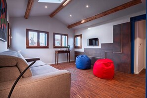 A modern living room with a sofa, bean bag, and a TV mounted on the wall. - Ca' Vida Terrazze (Venezia)