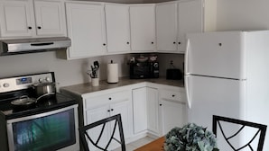 A kitchen with white cabinets, a black stove, a white refrigerator, and a microwave.