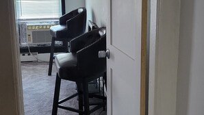 A room with a carpeted floor, a door, and a window with blinds.