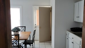 A kitchen with white cabinets, a wooden table, and chairs.
