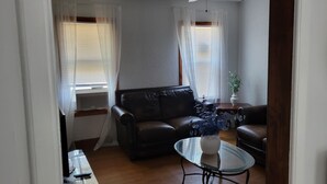 A living room with a leather sofa, a glass coffee table, and a potted plant.