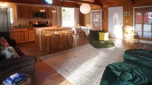 Amplia sala de estar con techo de madera, una cocina con isla central y una acogedora zona de estar.
