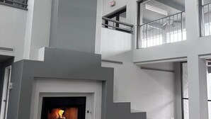 Een modern interieur met een open haard, een trap en een balkon.