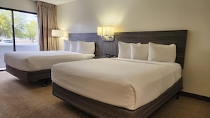 Een hotelkamer met twee bedden, een groot raam en uitzicht op buiten.