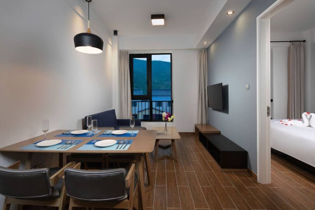 Et moderne hotelværelse med spiseplads, seng, fjernsyn og udsigt til bjergene.