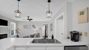 Una cucina moderna con mobili bianchi, un lavello in acciaio inossidabile e una macchina da caffè.
