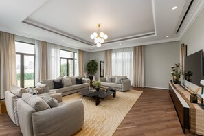 Un salón amplio con un gran sofá, una mesa de centro y un televisor sobre un mueble.