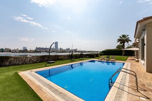 A swimming pool with a view of a city skyline and a body of water in the background.