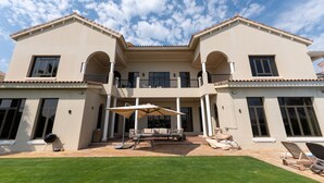Una casa de dos pisos con un patio que tiene muebles de exterior y una parrilla.