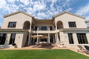 A two-story house with a patio area featuring outdoor furniture and a grill.