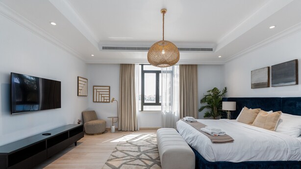Un dormitorio moderno con una cama grande, un televisor y una mesita consola.
