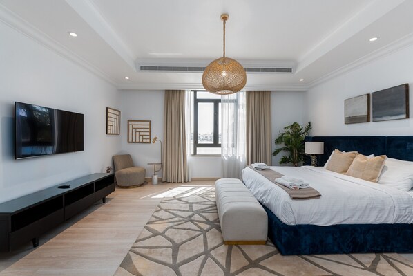 A modern bedroom with a large bed, a TV, and a console table.