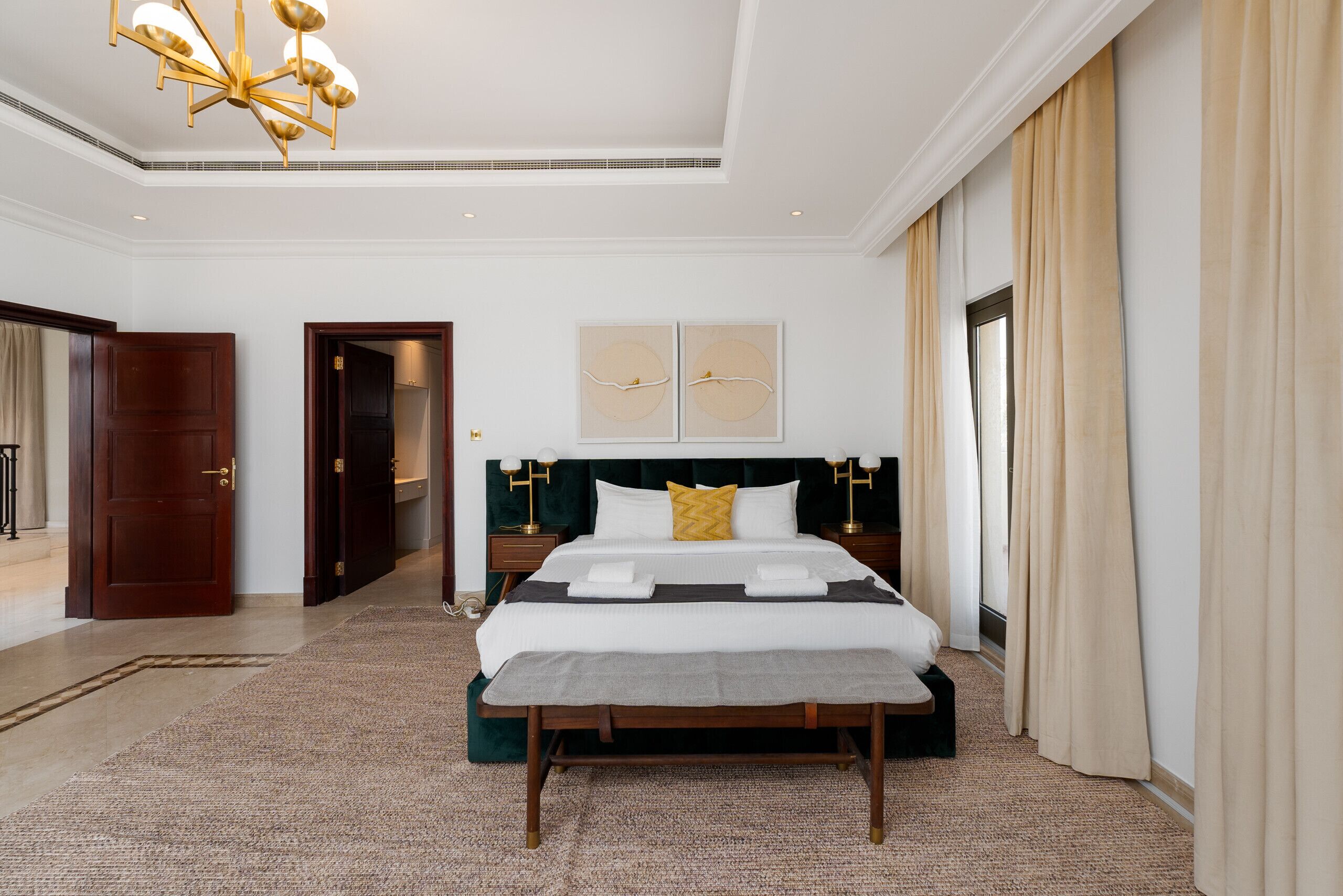Un'ampia camera d'albergo con un letto grande, un lampadario e vista sull'esterno.