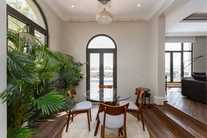 A modern dining area with a glass table, wooden chairs, and a large potted plant.