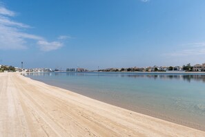 Une plage avec un ciel dégagé et une eau calme.