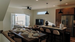 A modern kitchen with a dining area, wooden flooring, and a view to the outside.