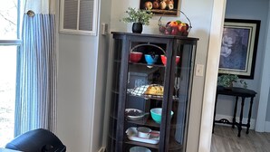 Een keuken met een zwart kastje, een raam met gordijnen en een schilderij aan de muur.