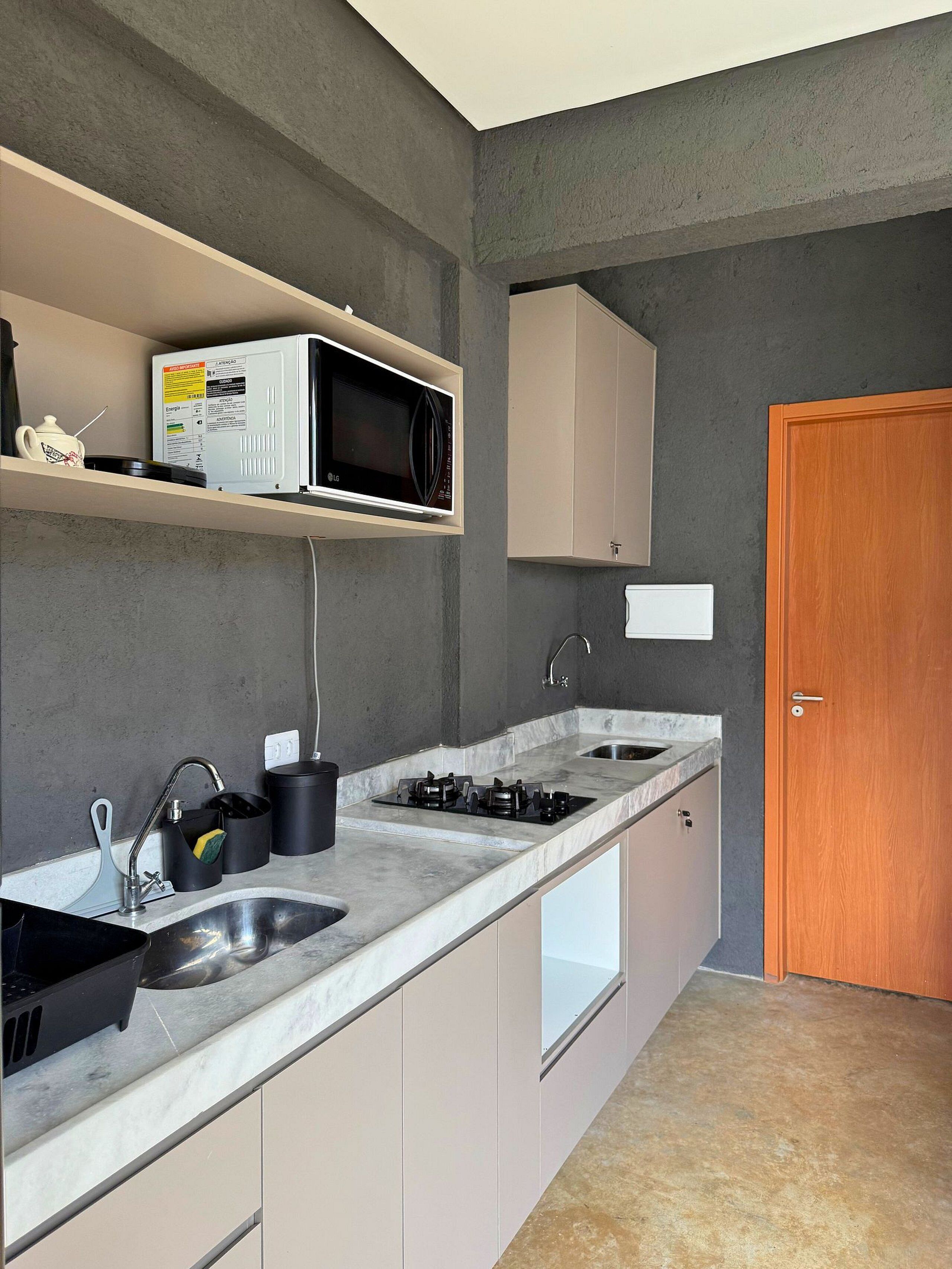 Una cocina con microondas, fregadero, estufa y alacenas.