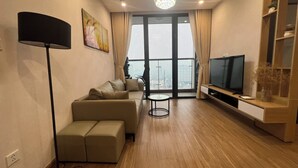 Ein modernes Wohnzimmer mit einer Couch, einem Fernseher und einem großen Fenster mit Blick auf die Stadt.