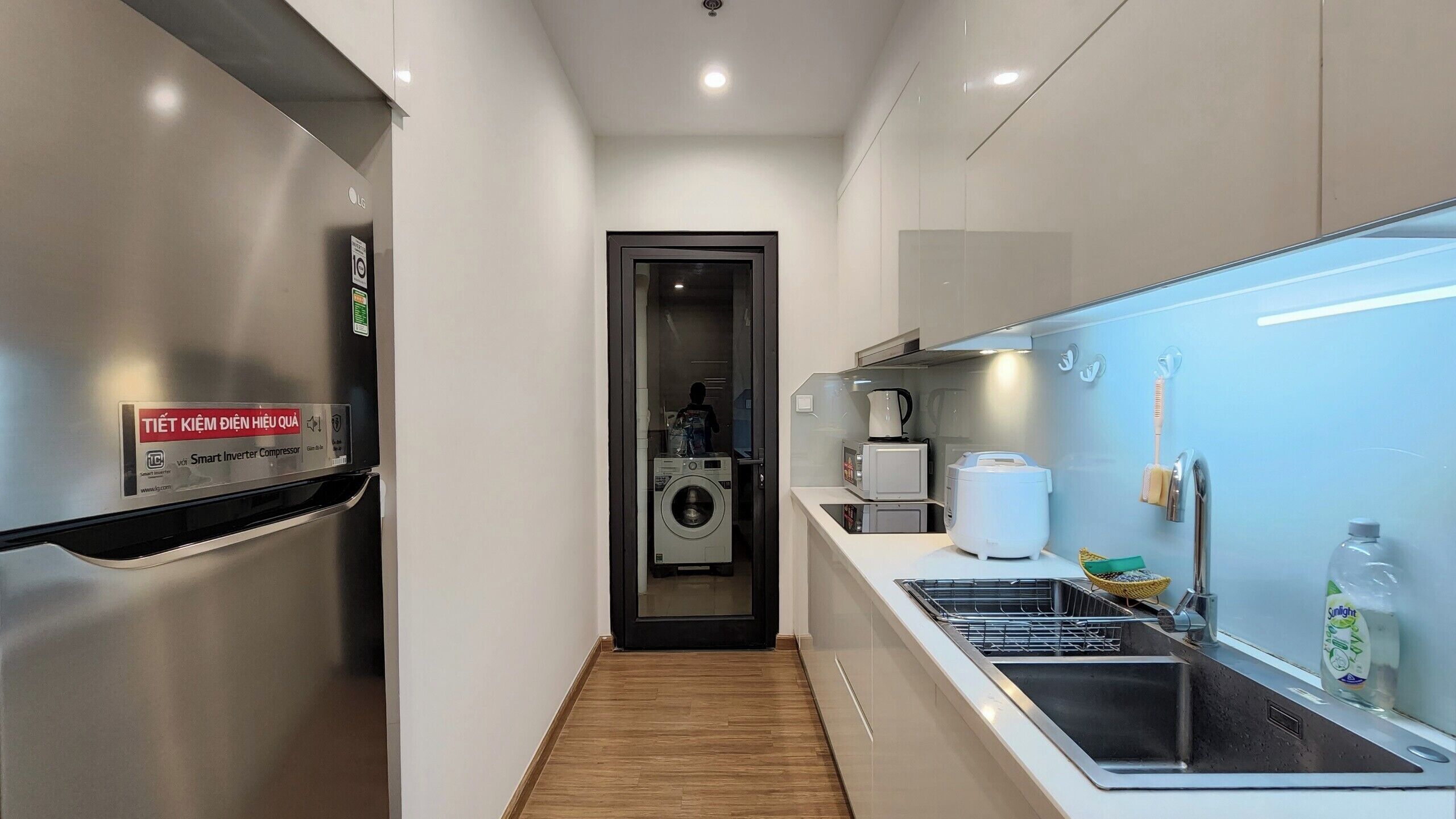 Une cuisine moderne équipée d’un réfrigérateur en acier inoxydable, d’un lave-linge et d’un four à micro-ondes.