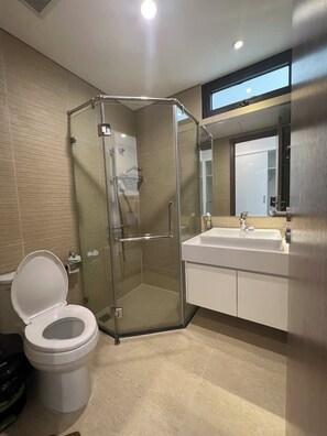 Een moderne badkamer met een douchecabine van glas, een wit wastafelmeubel en een toilet.