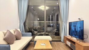 Ein modernes Wohnzimmer mit einer Couch, einem Couchtisch, einem Fernseher und einer Glastür, die auf einen Balkon führt.