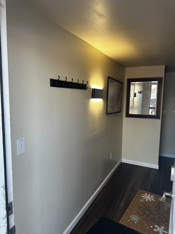 A hallway with a coat rack, a wall-mounted light, and a framed picture. - Cozy 2 Bedroom in Fairbanks with Wifi (Fairbanks)