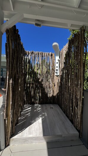 A covered outdoor area with a wooden fence, a white structure with a speaker, and a tiled floor. - Private Pool Tropical Escape (Jolly Harbour)