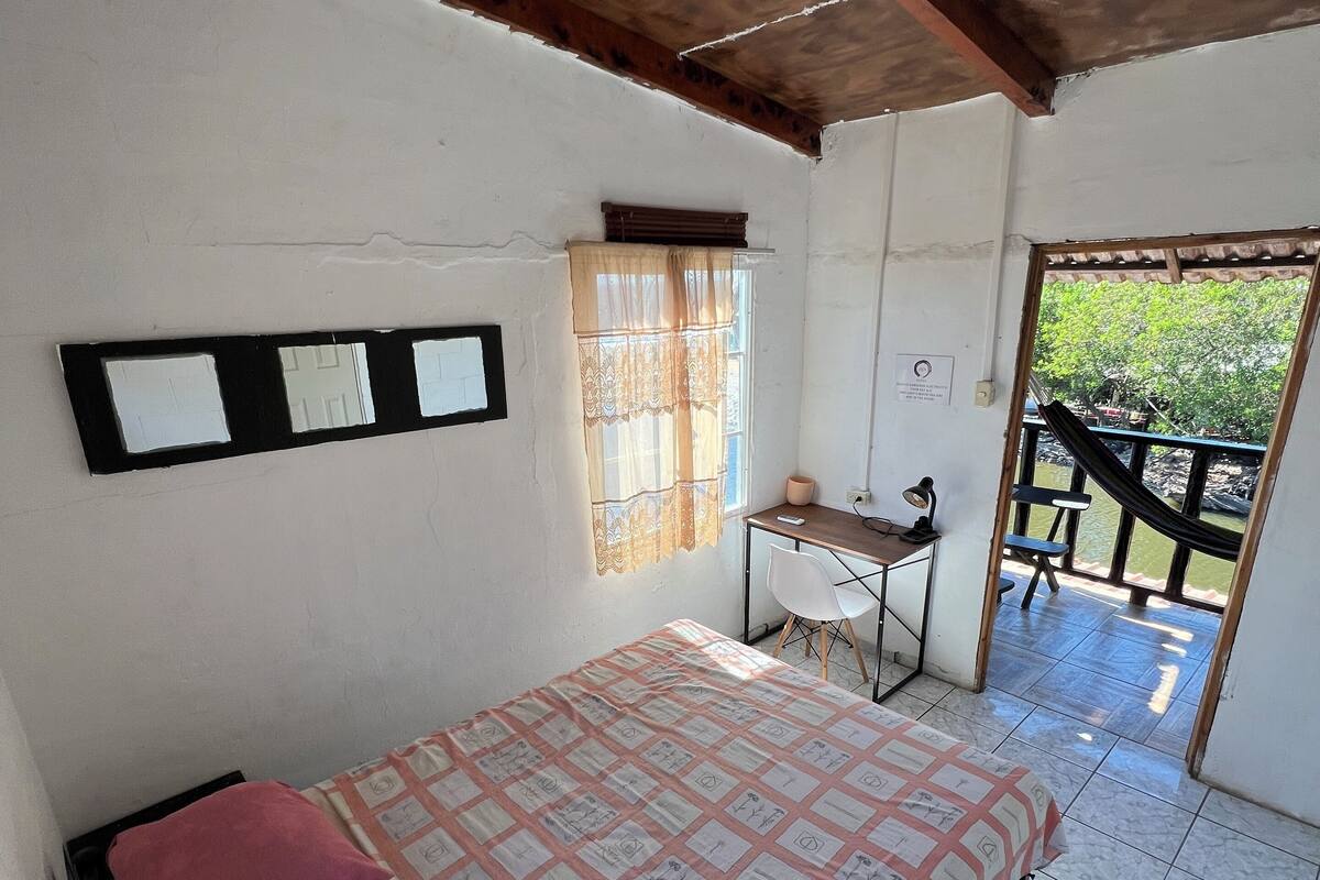 Een slaapkamer met een bed, een bureau en een raam met gordijnen.