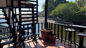 Un balcon donnant sur une rivière, avec des meubles en bois et des plantes en pot.