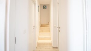 A narrow hallway with white walls and a beige carpeted staircase leading to a landing. - Villa Cycas by All4sardinia  (villasimius)