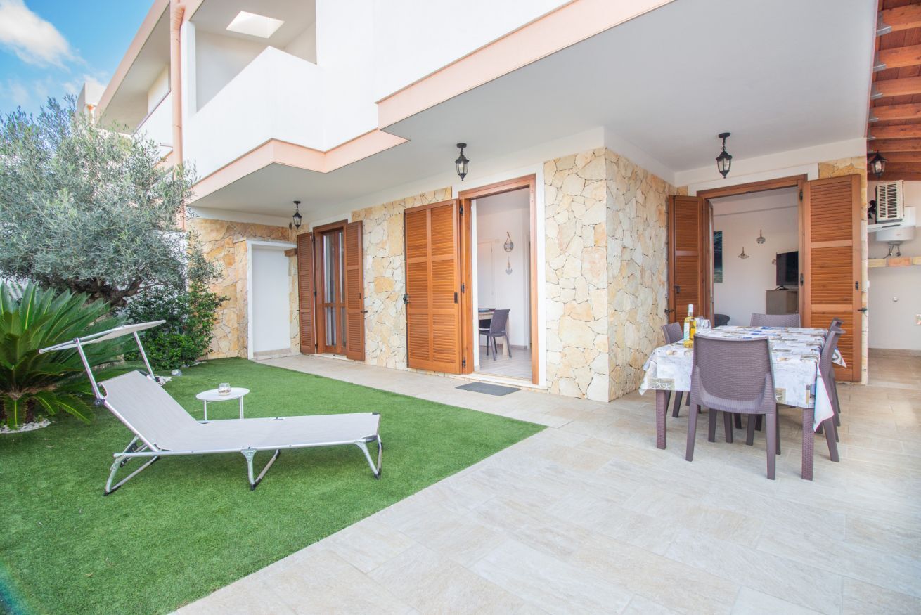 Une terrasse extérieure moderne, aménagée avec une table et des chaises pour les repas, un fauteuil de détente et une petite table ronde avec un verre.
