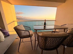 Ein Balkon mit Korbstühlen, einem Tisch und einer Champagnerflasche.