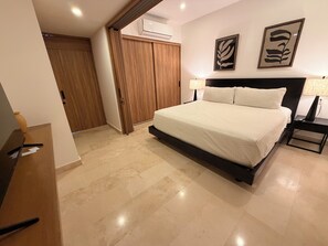 Een slaapkamer met een groot bed, een houten garderobe en twee kunstwerken aan de muur.