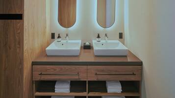 A bathroom with two sinks, wooden vanity, and two mirrors.