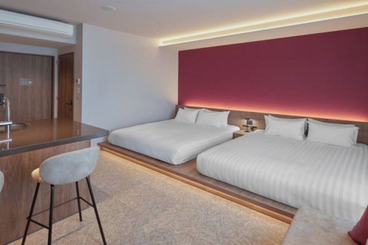 A hotel room with two beds, a desk, and a chair.