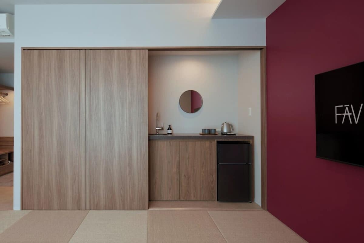 A modern kitchen with a built-in refrigerator, a round mirror, and a countertop with a kettle and a soap dispenser.