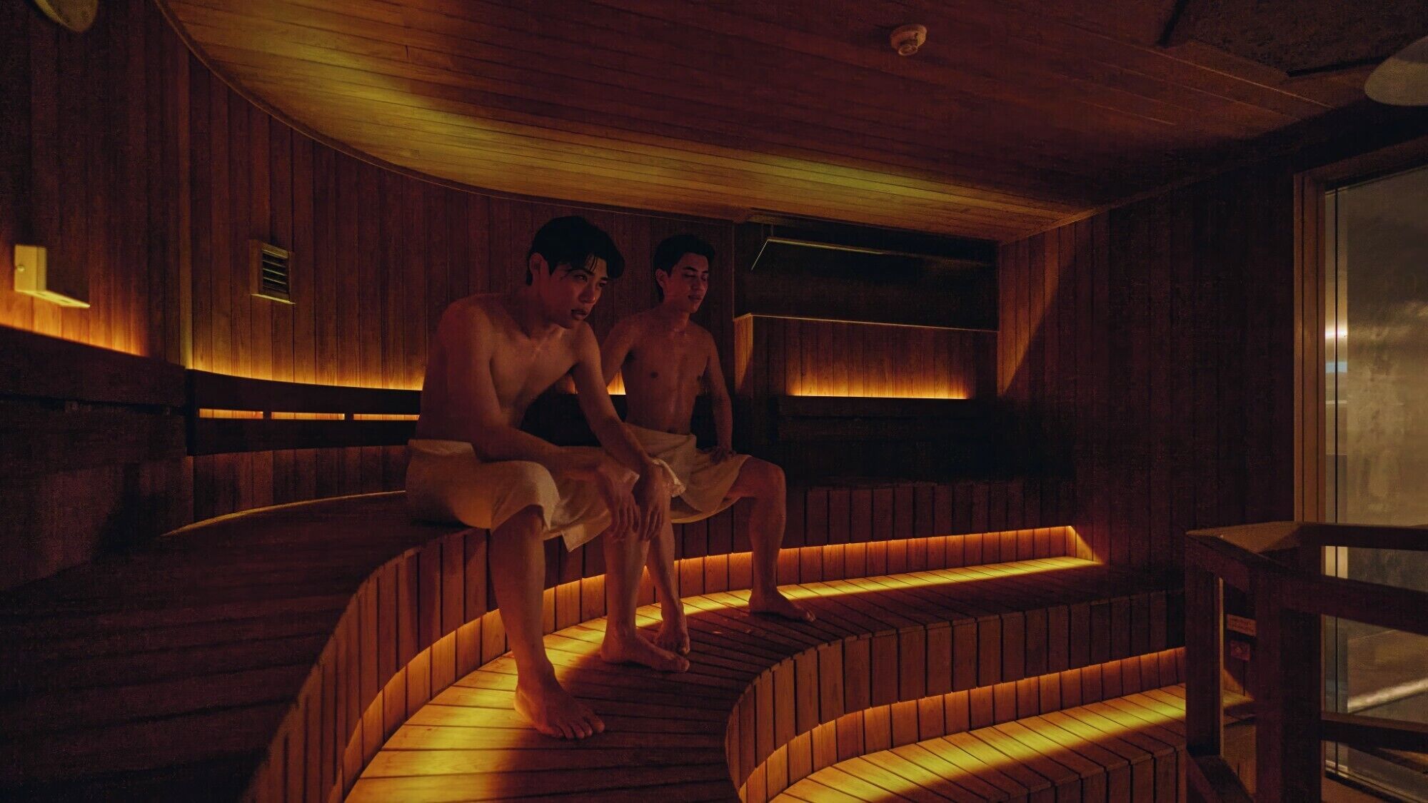 A sauna with wooden benches and a glass wall.