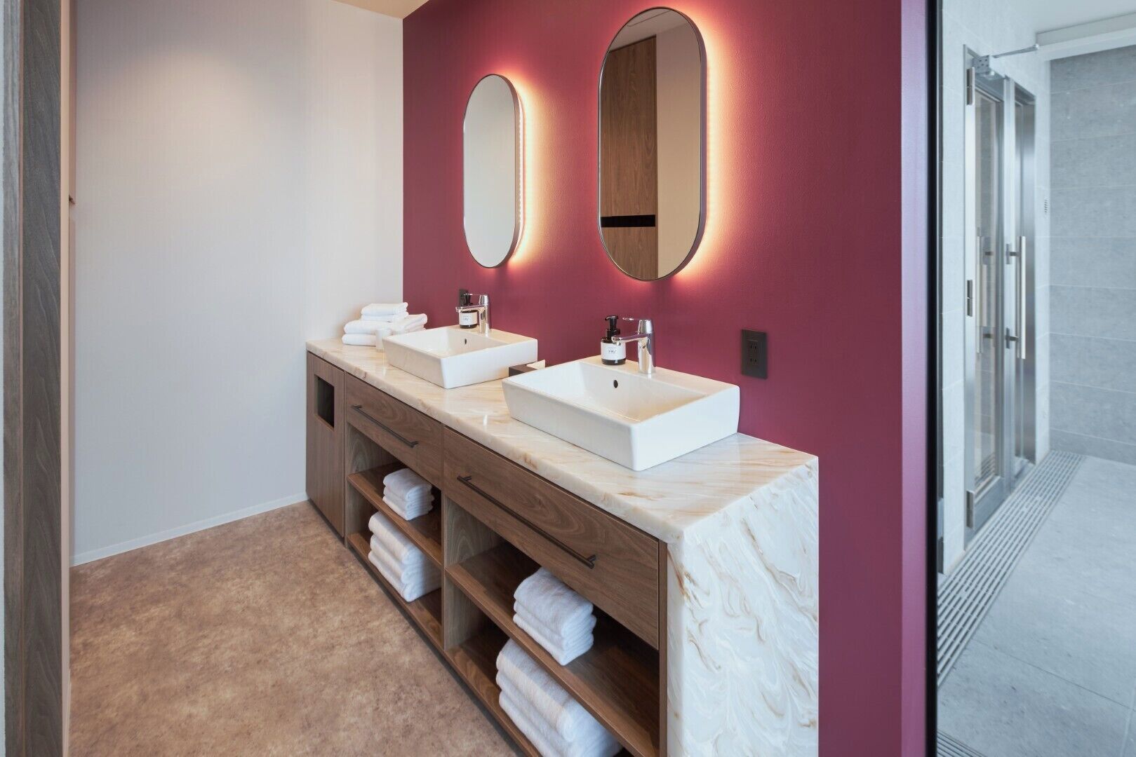 A modern bathroom with two sinks, wooden cabinetry, and a marble countertop.