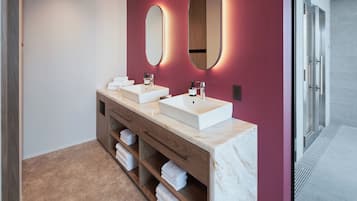 A modern bathroom with two sinks, wooden cabinetry, and a marble countertop.