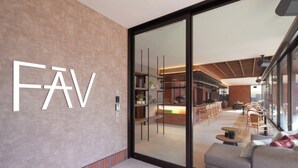 A modern interior with a large 'FAV' sign on the wall, a kitchen area visible through glass doors, and a seating area with tables and chairs. - FAV LUX Sapporo Susukino (Sapporo)