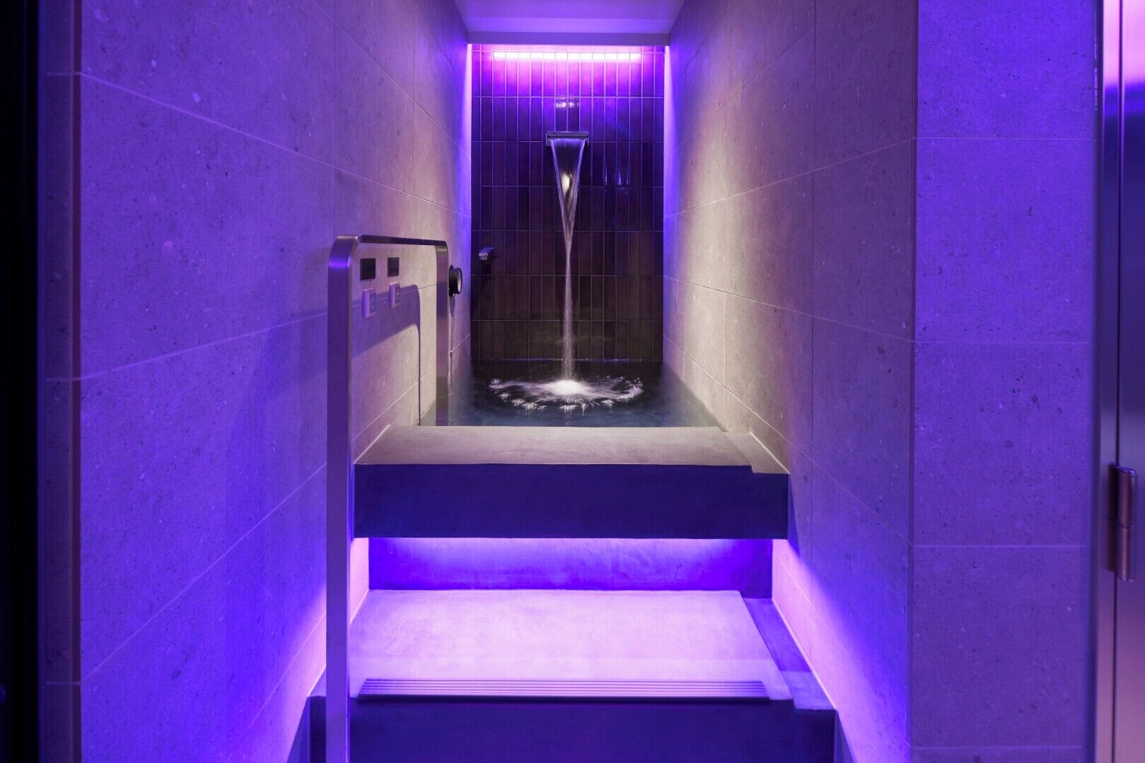 Une salle de bain moderne équipée d’une douche, d’une baignoire et d’une petite marche menant à l’espace douche.